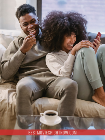 Happy black couple on couch with smartphone